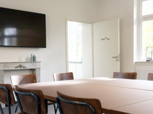 Blick in den Seminarraum "Pavillon" mit Konferenztischen und Flatscreen